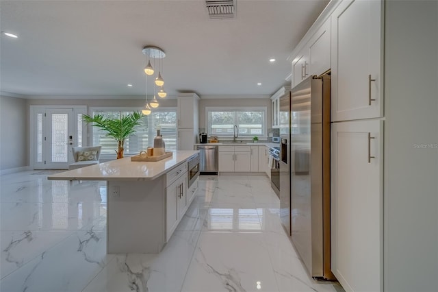 kitchen featuring a kitchen island, sink, white cabinets, hanging light fixtures, and stainless steel appliances