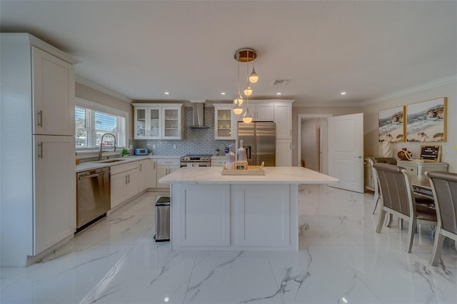 kitchen with pendant lighting, sink, appliances with stainless steel finishes, a kitchen island, and wall chimney exhaust hood