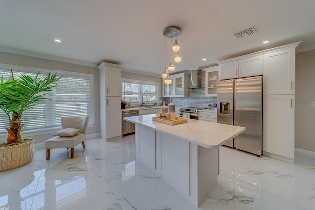 kitchen with white cabinetry, wall chimney range hood, decorative light fixtures, and appliances with stainless steel finishes