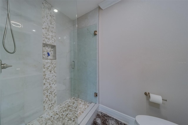 bathroom featuring a shower with shower door and toilet