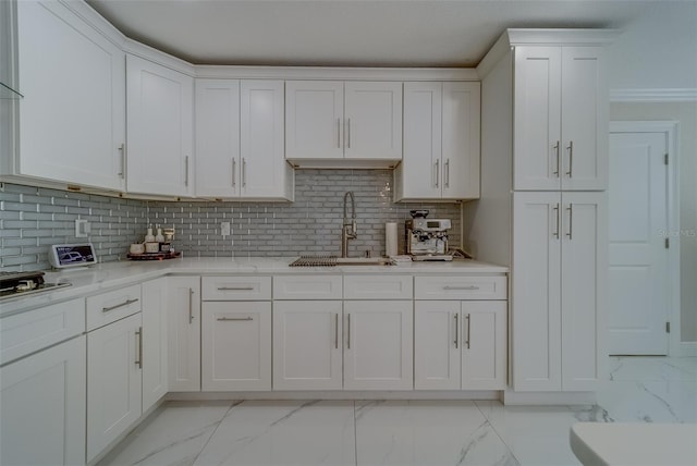 kitchen featuring sink, backsplash, light stone countertops, and white cabinets