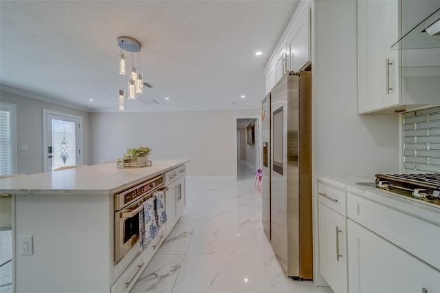 kitchen featuring stainless steel appliances, a center island, tasteful backsplash, white cabinets, and decorative light fixtures