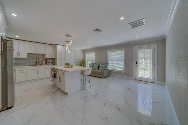 kitchen with sink, crown molding, tasteful backsplash, a kitchen island, and white cabinets