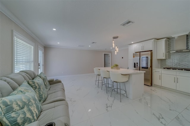 kitchen with appliances with stainless steel finishes, decorative light fixtures, white cabinetry, a kitchen bar, and a center island