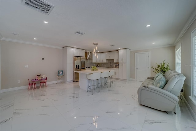 interior space featuring stainless steel fridge, a kitchen bar, hanging light fixtures, a center island, and crown molding