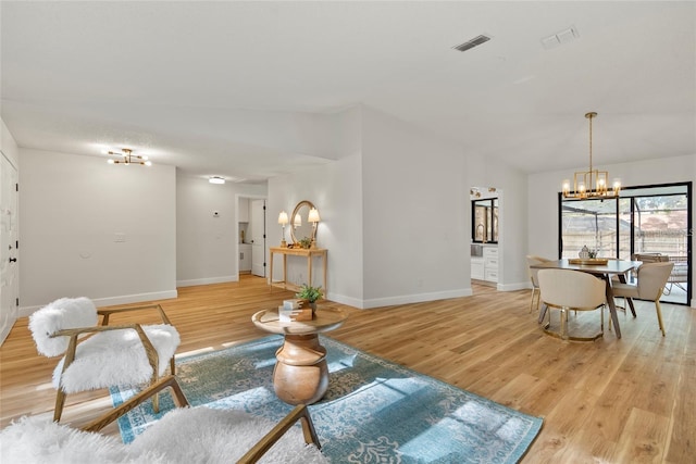 living room with lofted ceiling, a chandelier, and light wood-type flooring