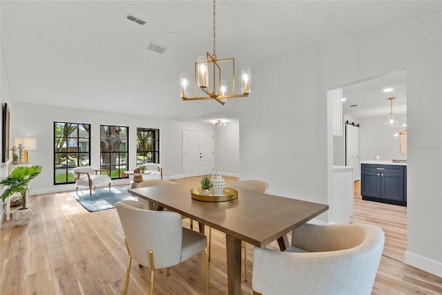 dining room featuring a barn door, a chandelier, and light hardwood / wood-style floors