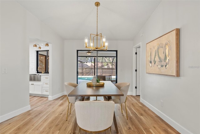 dining room featuring vaulted ceiling, sink, an inviting chandelier, and light wood-type flooring