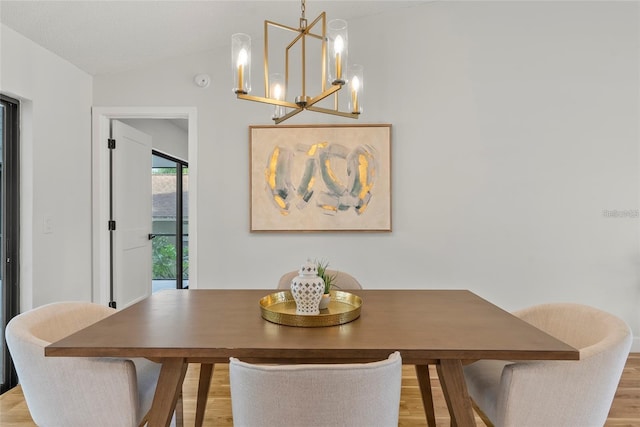 dining area featuring a chandelier, light hardwood / wood-style floors, and vaulted ceiling