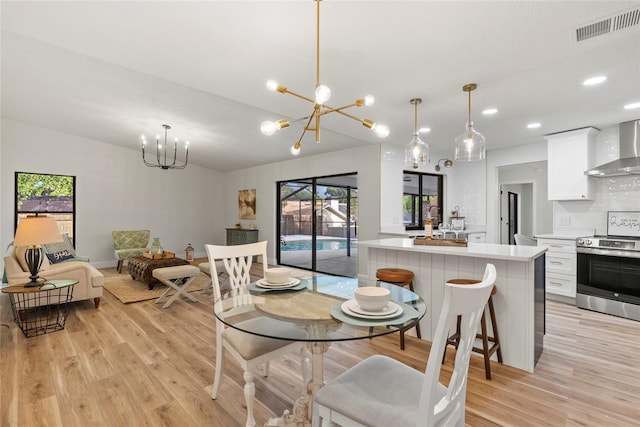 dining area with lofted ceiling, a notable chandelier, and light wood-type flooring