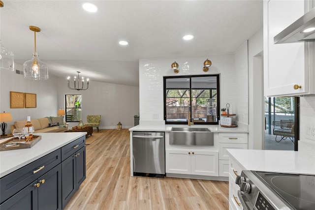 kitchen with wall chimney exhaust hood, sink, white cabinetry, hanging light fixtures, and stainless steel appliances