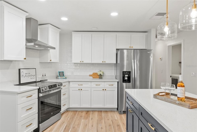 kitchen with white cabinetry, hanging light fixtures, light stone counters, stainless steel appliances, and wall chimney exhaust hood