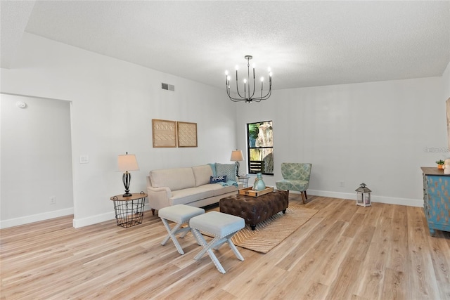 living room with a notable chandelier, a textured ceiling, and light hardwood / wood-style flooring