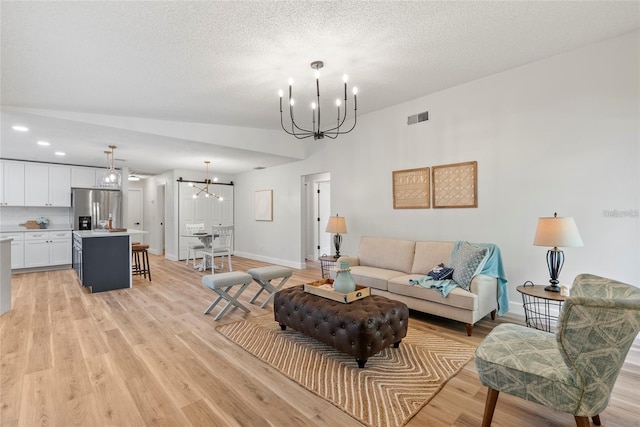 living room featuring an inviting chandelier, a textured ceiling, and light wood-type flooring