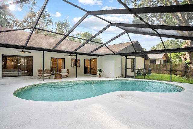 view of swimming pool with ceiling fan, glass enclosure, and a patio area