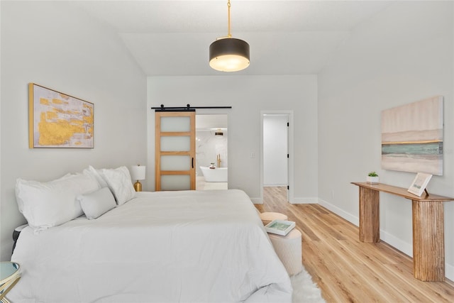 bedroom with lofted ceiling, wood-type flooring, and a barn door