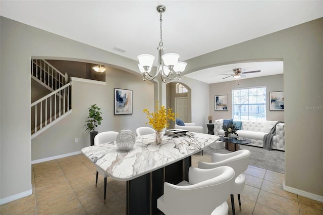 tiled dining room with ceiling fan with notable chandelier