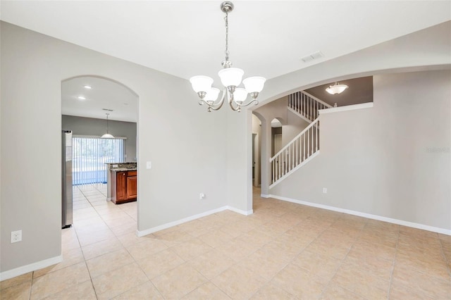 tiled spare room with an inviting chandelier