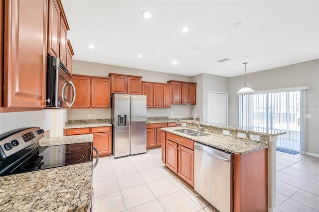 kitchen featuring sink, light stone counters, hanging light fixtures, stainless steel appliances, and a kitchen island with sink