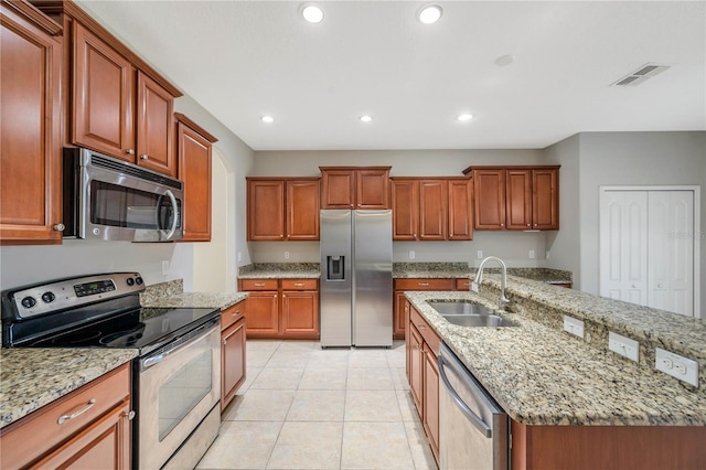 kitchen featuring sink, a kitchen island with sink, light tile patterned floors, light stone counters, and stainless steel appliances