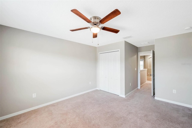 unfurnished bedroom with light colored carpet, ceiling fan, and a closet