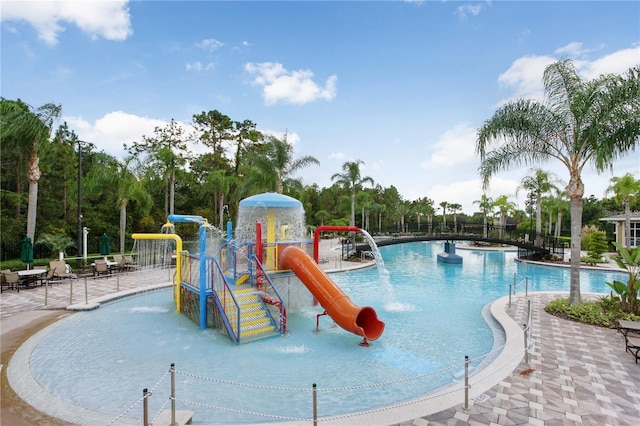 exterior space featuring pool water feature, a water slide, a playground, and a patio