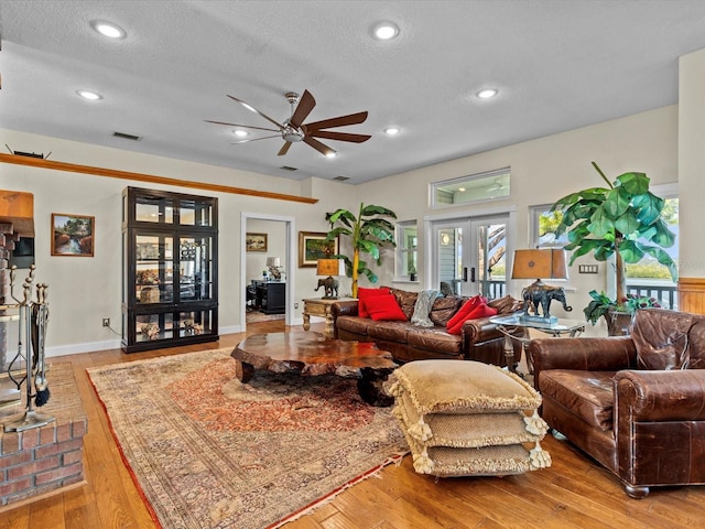 living room featuring french doors, ceiling fan, a textured ceiling, and light wood-type flooring