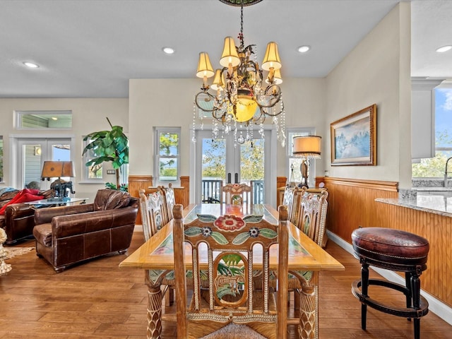 dining space with french doors, a healthy amount of sunlight, light hardwood / wood-style flooring, and a notable chandelier