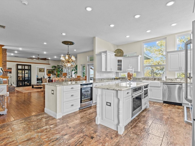 kitchen with white cabinetry, decorative light fixtures, stainless steel appliances, and a center island