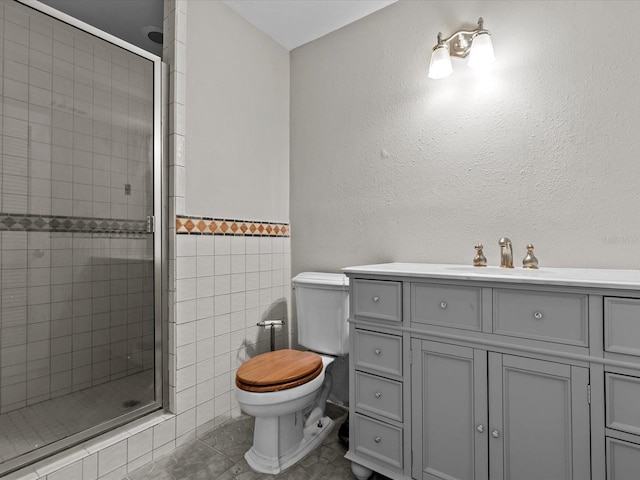 bathroom with vanity, toilet, a shower with shower door, and tile patterned flooring