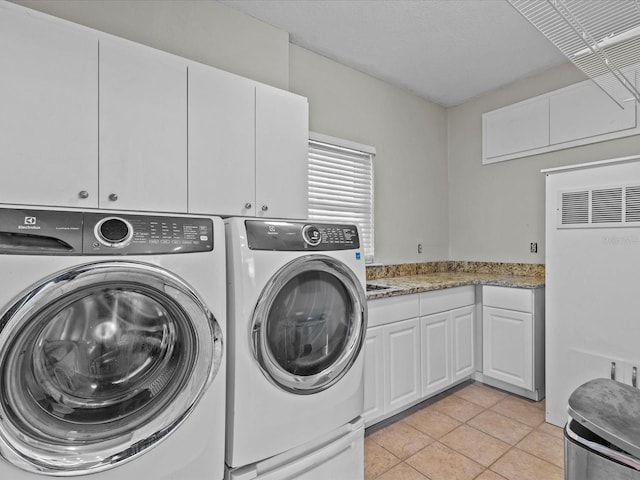 laundry room with cabinets, a textured ceiling, washer and dryer, and light tile patterned floors