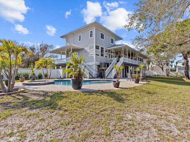 rear view of property featuring a lawn, a patio area, and a pool with hot tub