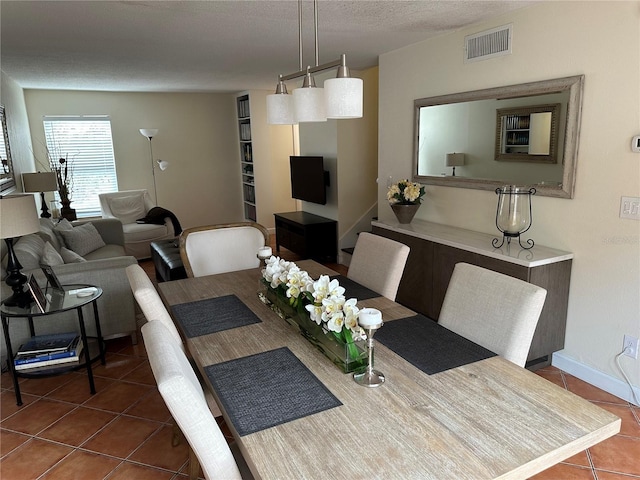 dining area featuring dark tile patterned flooring and a textured ceiling