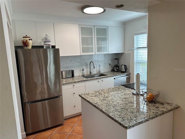 kitchen with stainless steel appliances, white cabinetry, sink, and light stone counters