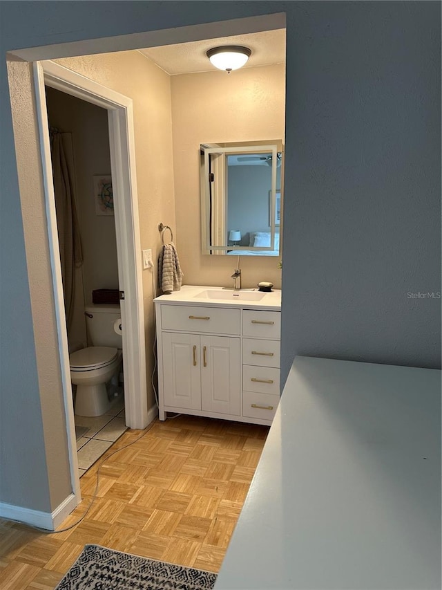 bathroom featuring vanity, parquet floors, and toilet