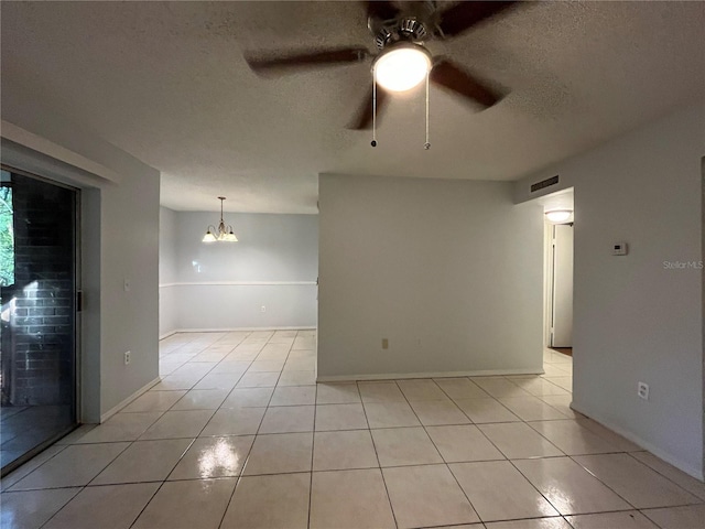 tiled empty room featuring ceiling fan with notable chandelier and a textured ceiling