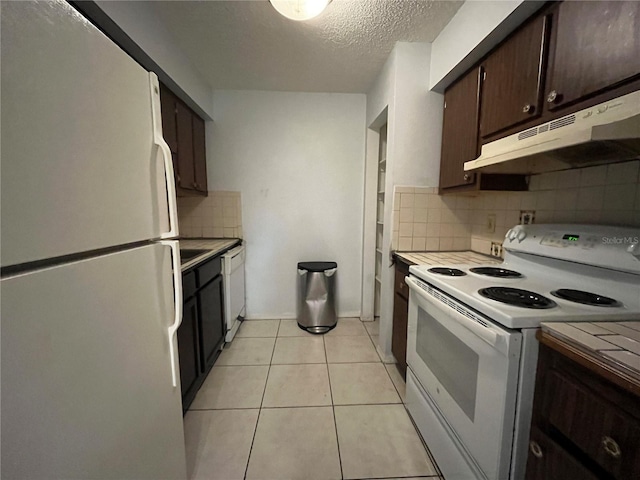 kitchen with decorative backsplash, light tile patterned floors, white appliances, dark brown cabinets, and a textured ceiling