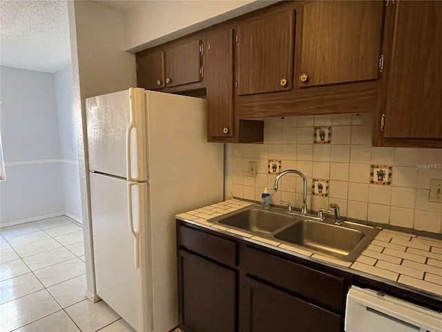 kitchen with light tile patterned flooring, sink, a textured ceiling, white appliances, and backsplash