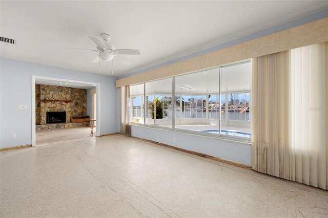 unfurnished living room with ceiling fan, a water view, and a fireplace