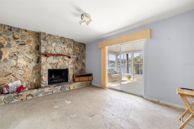 unfurnished living room with a fireplace, concrete flooring, and a water view