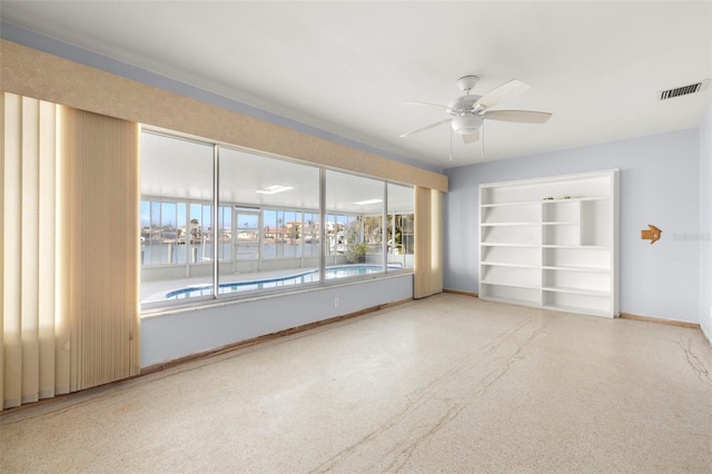 spare room featuring a water view, ceiling fan, and built in shelves