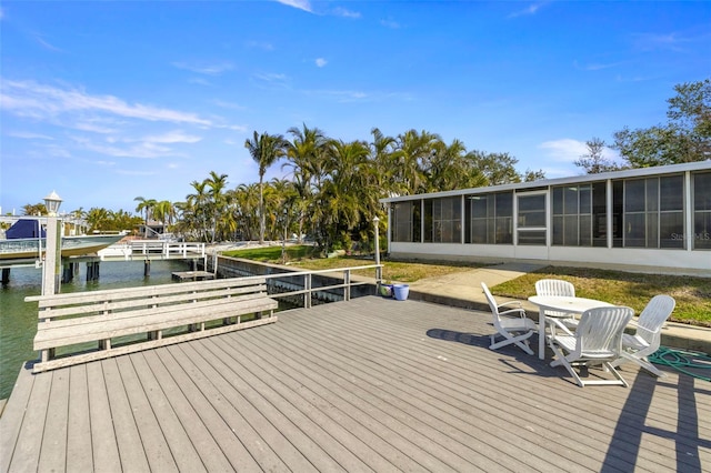 deck with a water view, a dock, and a sunroom