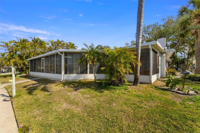 view of property exterior featuring a sunroom and a lawn