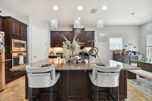 kitchen with hanging light fixtures, appliances with stainless steel finishes, a center island, and a kitchen breakfast bar