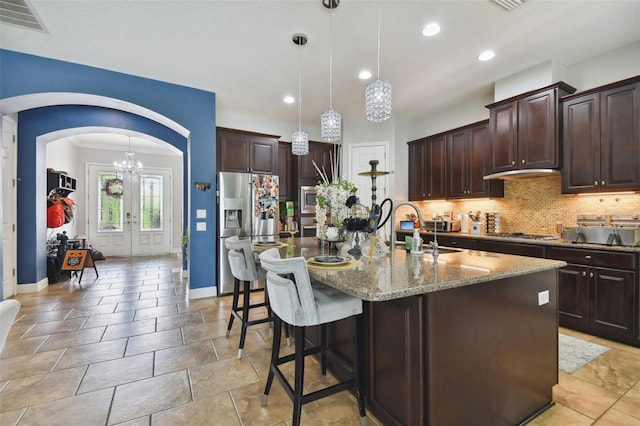 kitchen featuring french doors, sink, decorative light fixtures, a center island with sink, and stainless steel appliances