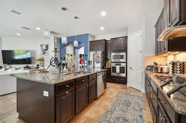 kitchen with dark brown cabinetry, sink, decorative light fixtures, a center island with sink, and stainless steel appliances