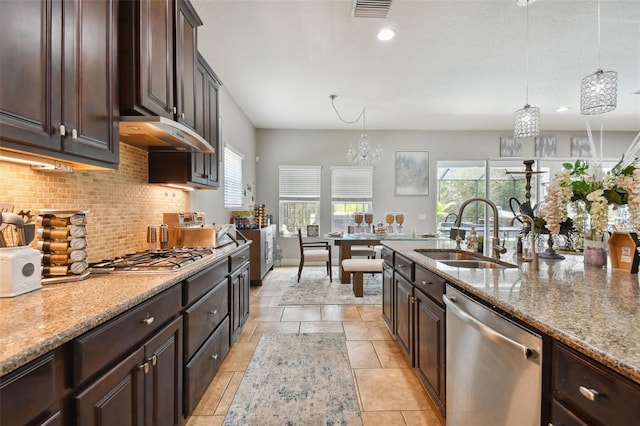 kitchen featuring sink, hanging light fixtures, dark brown cabinetry, stainless steel appliances, and light stone countertops