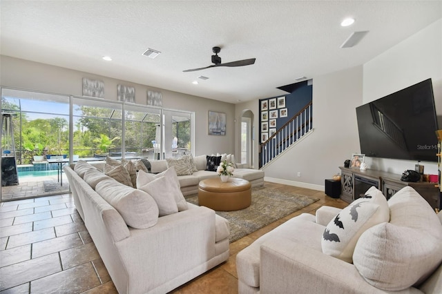 living room with ceiling fan and a textured ceiling