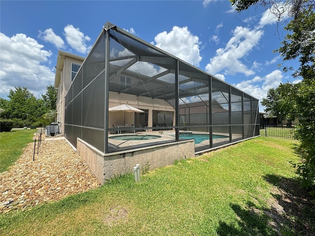 rear view of house with a yard, central AC unit, and a pool with hot tub