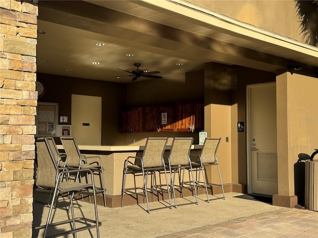 kitchen with ceiling fan, a kitchen breakfast bar, kitchen peninsula, and beam ceiling